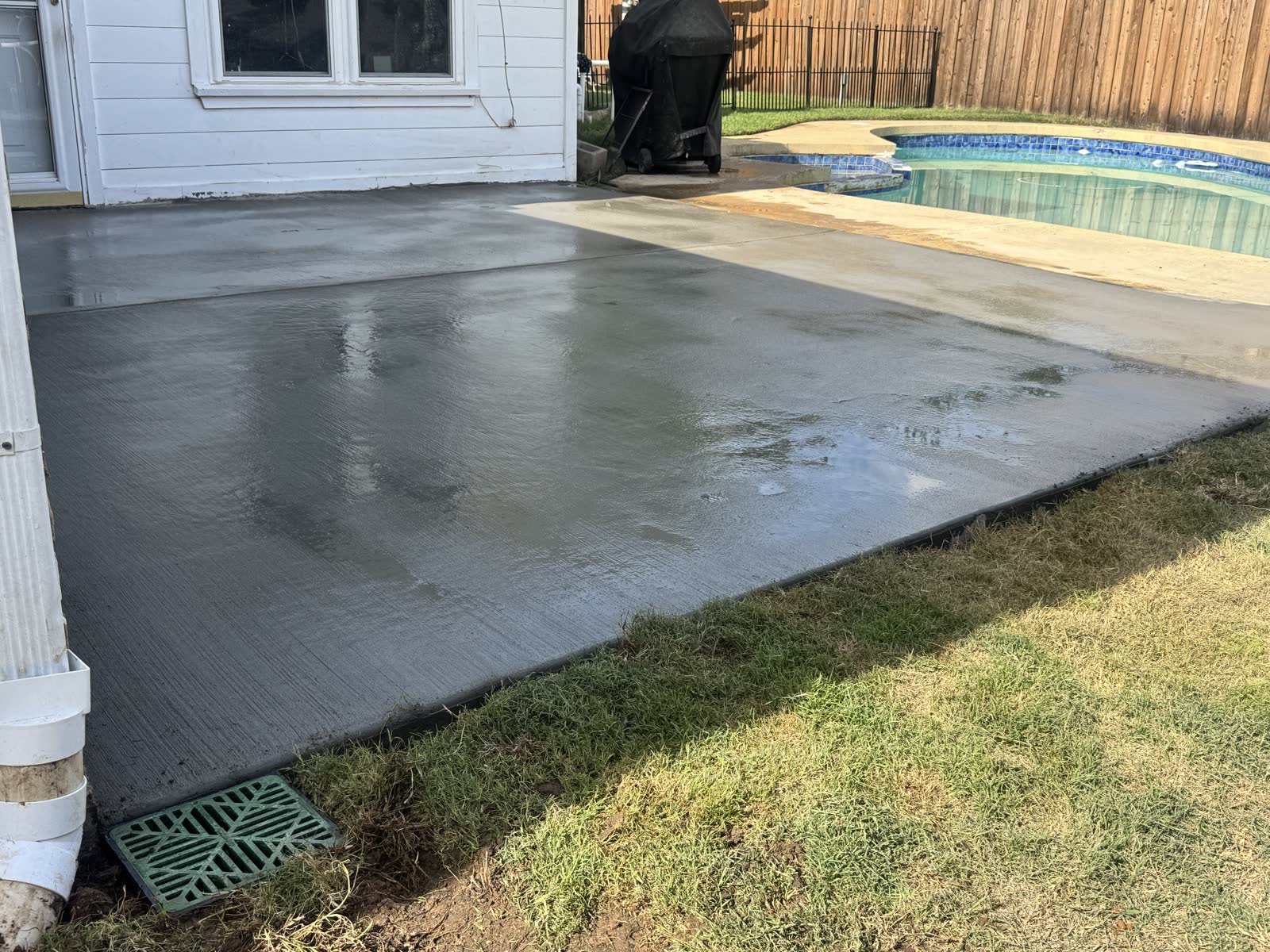 Waterline patio drainage project with new concrete and a surface drain by the downspout